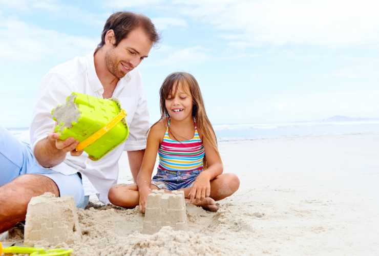 Bambina che costruisce un castello di sabbia